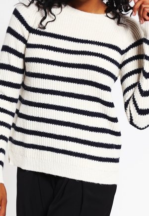 Maglione a maglia crema con righe orizzontali blu marina, caratterizzato da una texture a coste e maniche lunghe. Design con collo a girocollo e vestibilità rilassata.