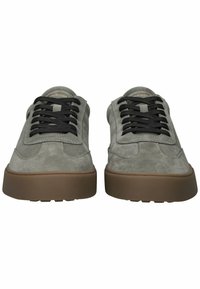 Pilkos zomšinės sportbačiai su juodomis raišteliais, apvaliu priekiniu galiuku ir rudu guminiais padu. Dizainas pasižymi siuvinėjimo akcentais ir žemu profiliu.