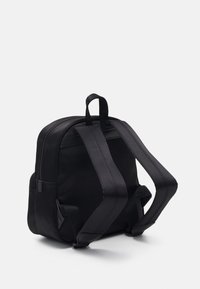 Svart ryggsäck i slät tyg, med justerbara remmar, ett handtag på toppen och dragkedjestängning. Enkel och funktionell design.