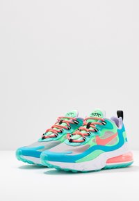 Sportskor i blått, grönt och rosa med nät- och syntetmaterial, tjock sula och synlig Air-dämpning.