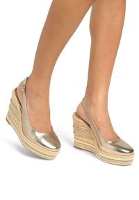 Gouden metallic wedge schoenen met een slingback ontwerp, voorzien van een textuur zoals stro op de zool en een glad bovenoppervlak. Accentueerde randen.