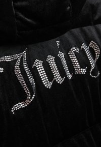 Crna kadifa hoodie s kristalnim ukrasima koji slove "Juicy" u različitim veličinama, s mekim teksturom i prilagođenim dizajnom.