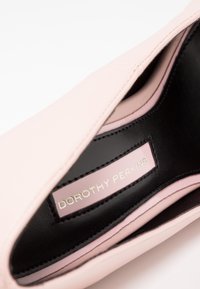 Ljusrosa lädersko med en slät yta, med en svart foder och en etikett som läser "DOROTHY PERKINS" i silver.