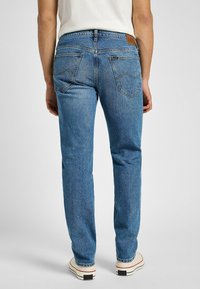 Blå denimjeans med rak passform, som har bakfickor, en läderlogotyp på midjan och en klassisk blekt finish.