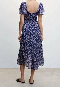 Robe midi bleue à fleurs avec des manches courtes et volantes, un dos arrondi et un ourlet fluide. Le tissu semble léger et semi-transparent.