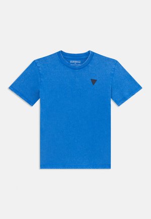 Tricou scurt cu mânecă, de culoare albastru deschis, cu un mic logo triunghiular negru în zona stângă a pieptului. Fundal alb simplu.