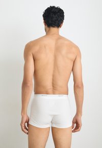Boxeri din bumbac alb cu un brâu elastic gri, având logo-ul "GANT". Textură netedă, design ajustat și croială de înălțime medie.