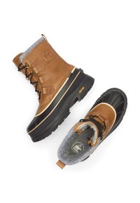 Ruskeat nahkaiset talvikengät, joissa musta kumipohja, harmaa fleecvuori ja kestävä Vibram-pohja. Sisältää metalliset osat ja nauhat.