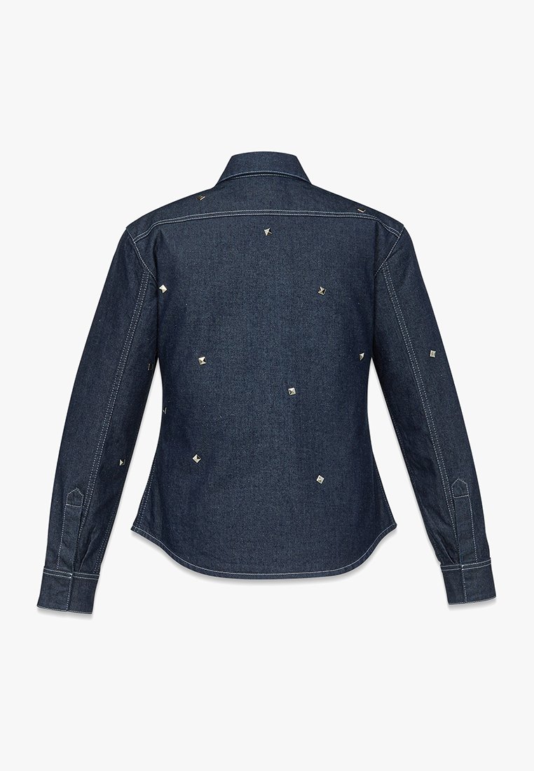 Ciemnoniebieska dżinsowa koszula z długim rękawem, na plecach ozdobiona drobnymi, srebrnymi kwadratowymi ćwiekami oraz białymi przeszyciami kontrastowymi.