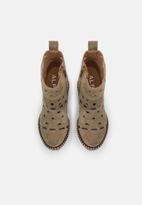 Stivaletti in camoscio verde oliva con design a taglio, fodera interna marrone, accenti neri e bordo intrecciato attorno alla suola.