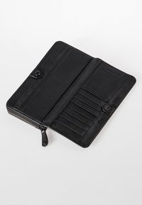 Portafoglio in pelle nera con chiusura a zip, slot per carte interne e scomparto a bottone. Tessuto liscio e design minimalista.