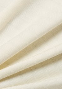 Teksturowana tkanina w odcieniu off-white, z subtelnym wzorem w paski i gładką fakturą, układająca się w fałdy.