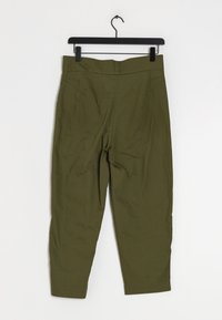 Pantalon vert olive suspendu à un cintre noir. Il présente une texture lisse, une taille haute et deux poches avant inclinées.