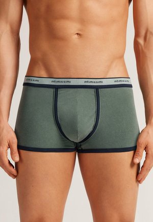 Grüne Baumwoll-Boxershorts mit einem marineblauen Bund. Sie verfügen über eine enganliegende Passform, Ziernähte und ein Design mit einer Fronttasche.