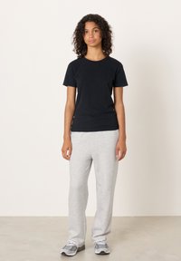 Čierne tričko s krátkym rukávom v kombinácii so sivými teplákmi. Tričko má okrúhly výstrih, tepláky majú voľný strih a elastický pás.