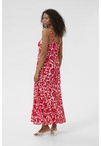Robe maxi rouge et blanche à fleurs avec bretelles ajustables et dos smocké, présentant un tissu léger et fluide ainsi qu'un ourlet à volants.