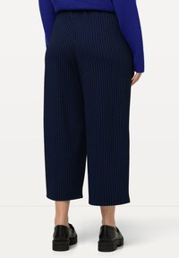 Pantalones culottes de rayas azul marino con un ajuste holgado y longitud recortada, que cuentan con una tela texturizada y sin bolsillos ni herrajes visibles.