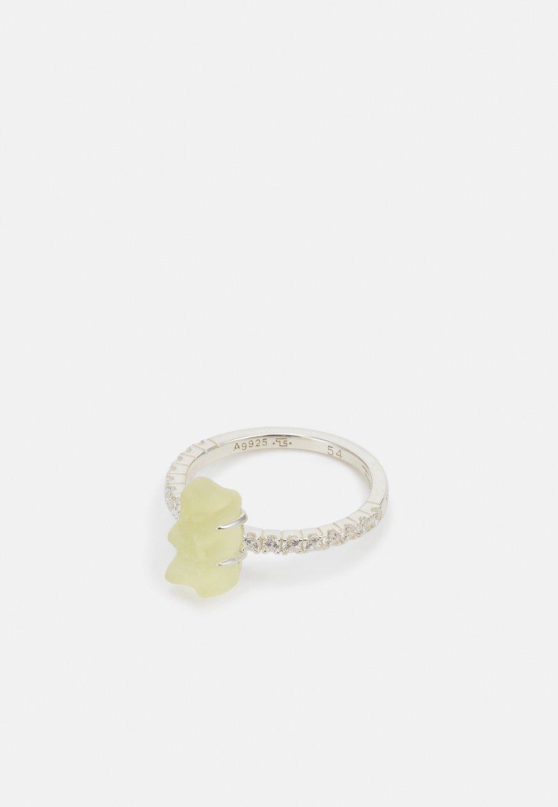 Hopeaketju hope ring, jossa on keltainen karkkihahmo, joka toimii keskipisteenä, ympärillä kiiltävä rivi kirkkaista kivistä.