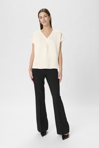 Ivory short-sleeve v-neck blouse paired with black flared trousers and pointed black heels, featuring a smooth texture and relaxed silhouette.