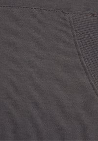 Tissu gris foncé à texture côtelée, avec des coutures visibles et un design de poche latérale. Le matériau est doux et extensible.