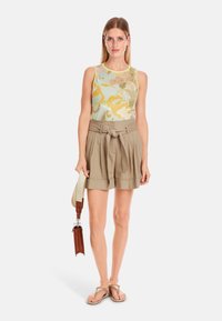 Tank top with floral pattern in green, yellow, and pink; paired with beige high-waisted shorts featuring a tie waist and pleats.