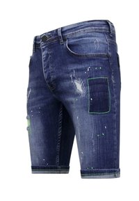 Denim shorts in donkerblauw met versleten details, groene stiksels, verfspatten en een zak op de voorkant.
