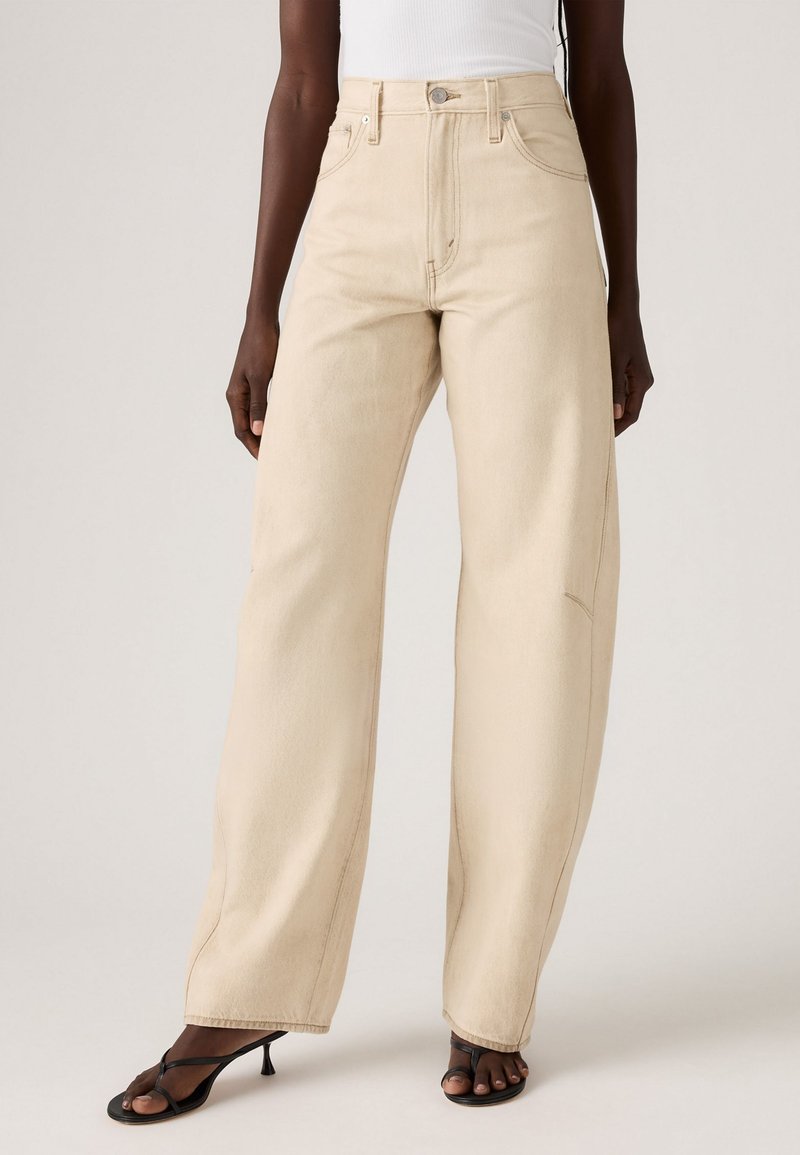 Beige wijde jeans van denim; hoog in de taille met voorzakken, zichtbare stiksels en een lichte vervaging.