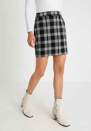 Black and white plaid mini skirt featuring a fitted silhouette and side pockets, paired with white ankle boots with block heels.