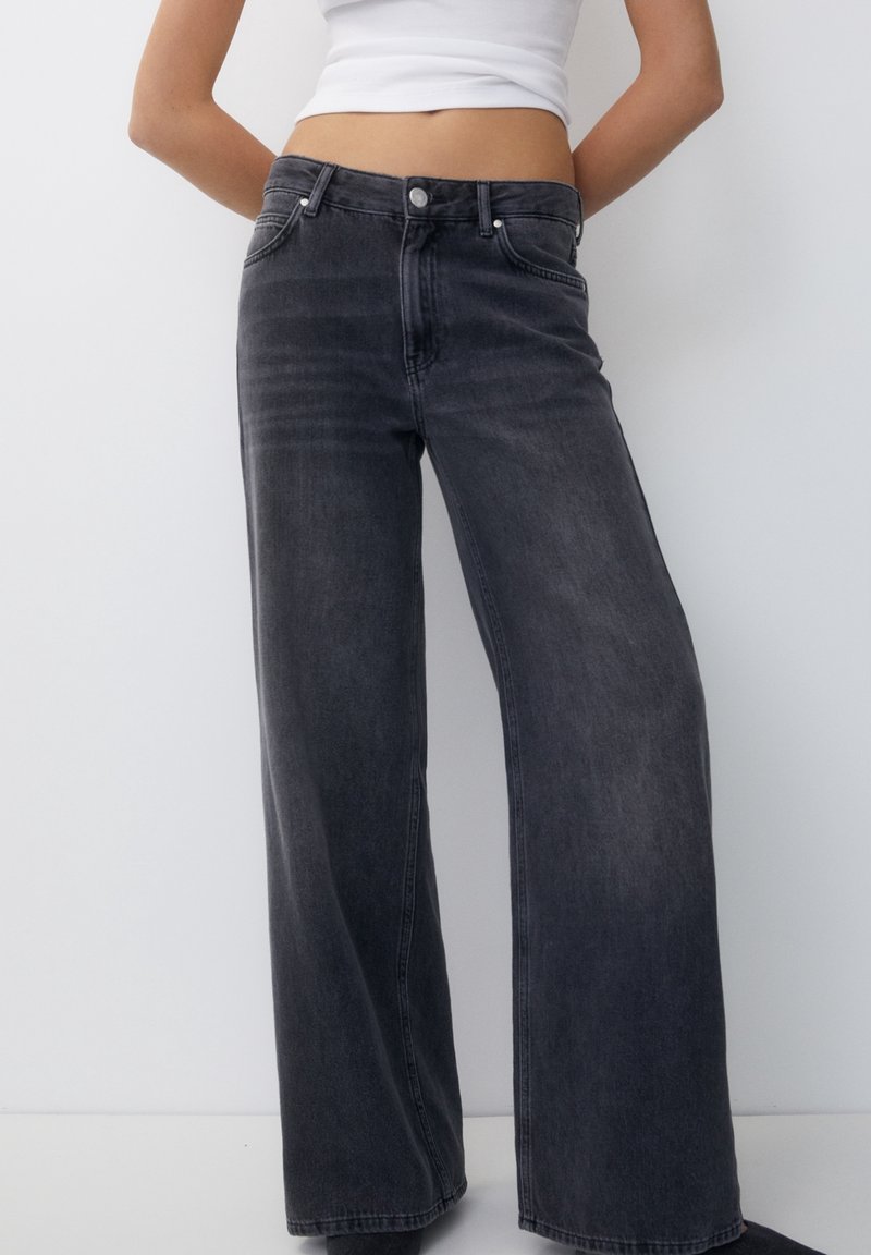 Wide-leg jeans in dark gray denim, featuring a high waist, front pockets, and a button closure. Smooth texture with subtle fading.