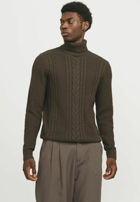 Maglione a collo alto in maglia marrone con motivi a treccia testurizzati, polsini a coste e design aderente. Realizzato in un materiale caldo e spesso.