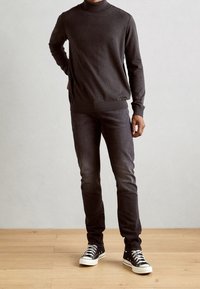 Tmavě šedý rolák, slim-fit džíny a černé vysoké tenisky s bílou podrážkou. Hladký povrch a přiléhavý střih.