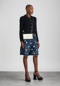 Svart ribbad tröja med krage, i kombination med blå denimshorts med vita blomstertryck. Bärs med svarta platåklackar.