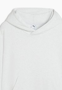 Sweat à capuche blanc avec poche avant, petit logo Puma sur la poitrine, et étiquette à l'intérieur de l'encolure.