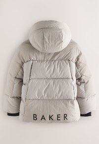 Puffiger beiger Jacke mit Kapuze, die gesteppten Abschnitte aufweist. Auf der Rückseite steht das Wort "BAKER" in fetten, schwarzen Buchstaben. Strukturierter Stoff.