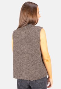 Grauer, flauschiger Strickwesten mit runder Halslinie und ärmellosem Design. Der Saum ist leicht geschwungen, was der Gesamtoptik Textur verleiht.
