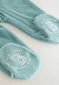 Calze in misto cotone di colore teal con una texture morbida. Presentano dettagli del logo bianco sulla suola, punta rotonda e design a maglia.