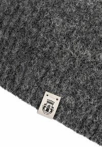 Dark gray textured knit fabric with a small beige tag displaying a crowned shield and two lions emblem at the edge.