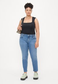Crni bodi s kvadratnim izrezom, svijetloplje odrezane traperice viskog struka, cipele u mint zelenoj boji i torba na pruge crno-bijela. Prikazan ležeran outfit.