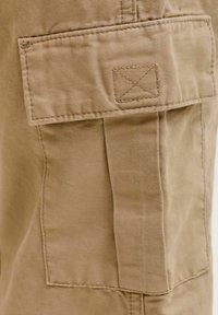 Chaki spalvos audinio cargo kišenė su atvartėliu ir sustiprintu siuvimu ant kelnių poros.