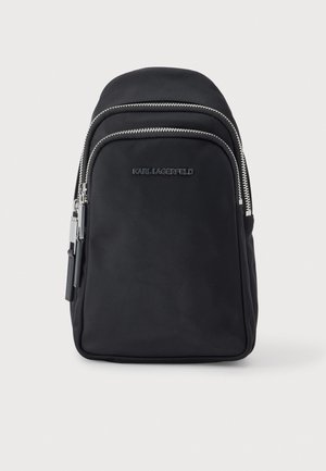 Sac à dos noir Karl Lagerfeld avec deux compartiments à fermeture éclair argentée, sur fond clair.