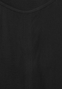 Tessuto nero con una superficie liscia, caratterizzato da un collo rotondo e cuciture visibili lungo il centro. Design minimalista e solido.