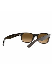 Occhiali da sole di colore marrone con montatura in plastica nera lucida e tempie larghe. Presentano un accento metallico vicino cerniera.