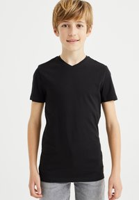 T-shirt nera a V, realizzata in cotone morbido, con maniche corte e design slim fit. Abbinata a jeans grigi chiari.