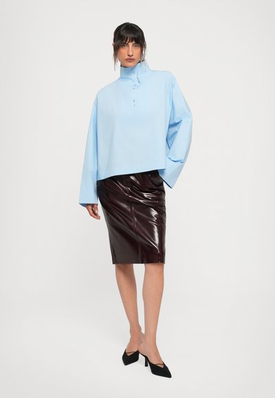 Light blue oversized shirt with high collar and button detailing, paired with a form-fitting dark burgundy, shiny latex pencil skirt. Black heels.