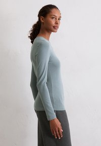Lichtblauw, lang mouwen top gemaakt van zacht, geribbeld materiaal; aansluitend ontwerp met een ronde hals, gecombineerd met donkergrijze onderkleding.
