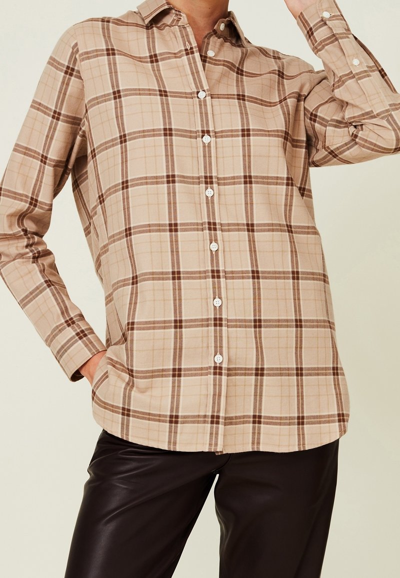 Camisa de cuadros beige con cuadros marrones y crema, de manga larga y con cuello clásico. Presenta botones blancos y un corte relajado.