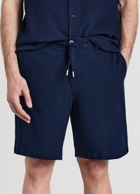 Marineblaue Shorts aus leichtem Stoff, mit Kordelzug in der Taille, seitlichen Taschen und einer glatten Textur mit sauberem Abschluss.