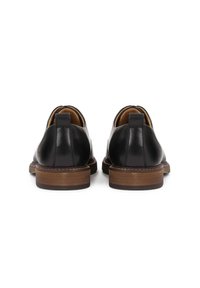 Scarpe in pelle nera dal design elegante. Presentano un collare imbottito, un tacco in legno marrone e cuciture in contrasto lungo la suola.
