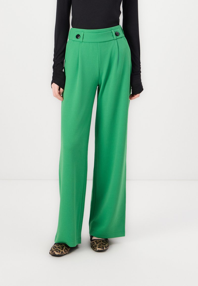 Pantalons larges verts en tissu lisse, dotés d'une taille haute, de plis et de deux boutons noirs à l'avant.