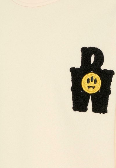 Maglione color crema con un motivo ricamato nero testurizzato, che presenta una faccina sorridente gialla e le lettere "R" e "W".